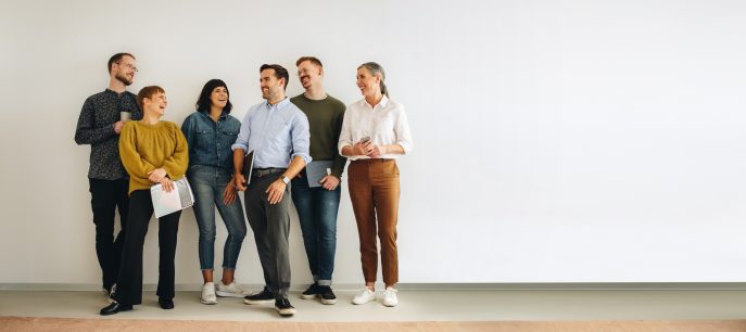 Diverse group of professionals standing and laughing in a modern workspace