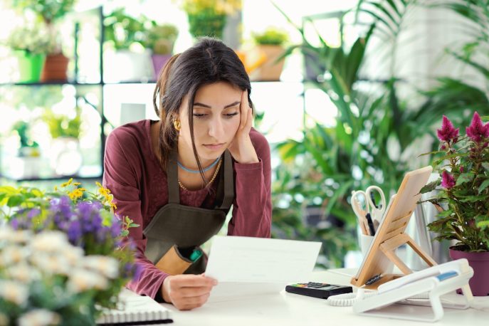 Worried florist reading financial documents at her desk