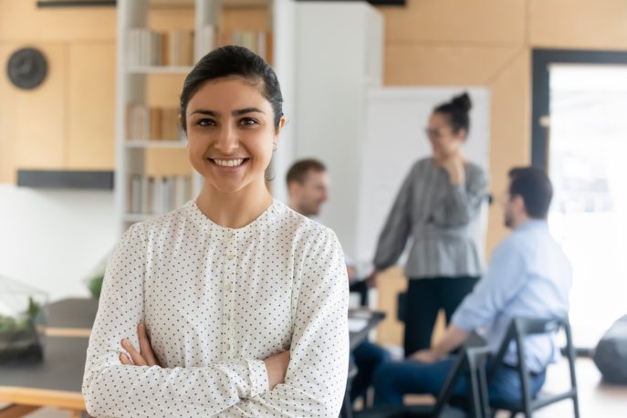 Confident young woman standing in front of a team in a modern office