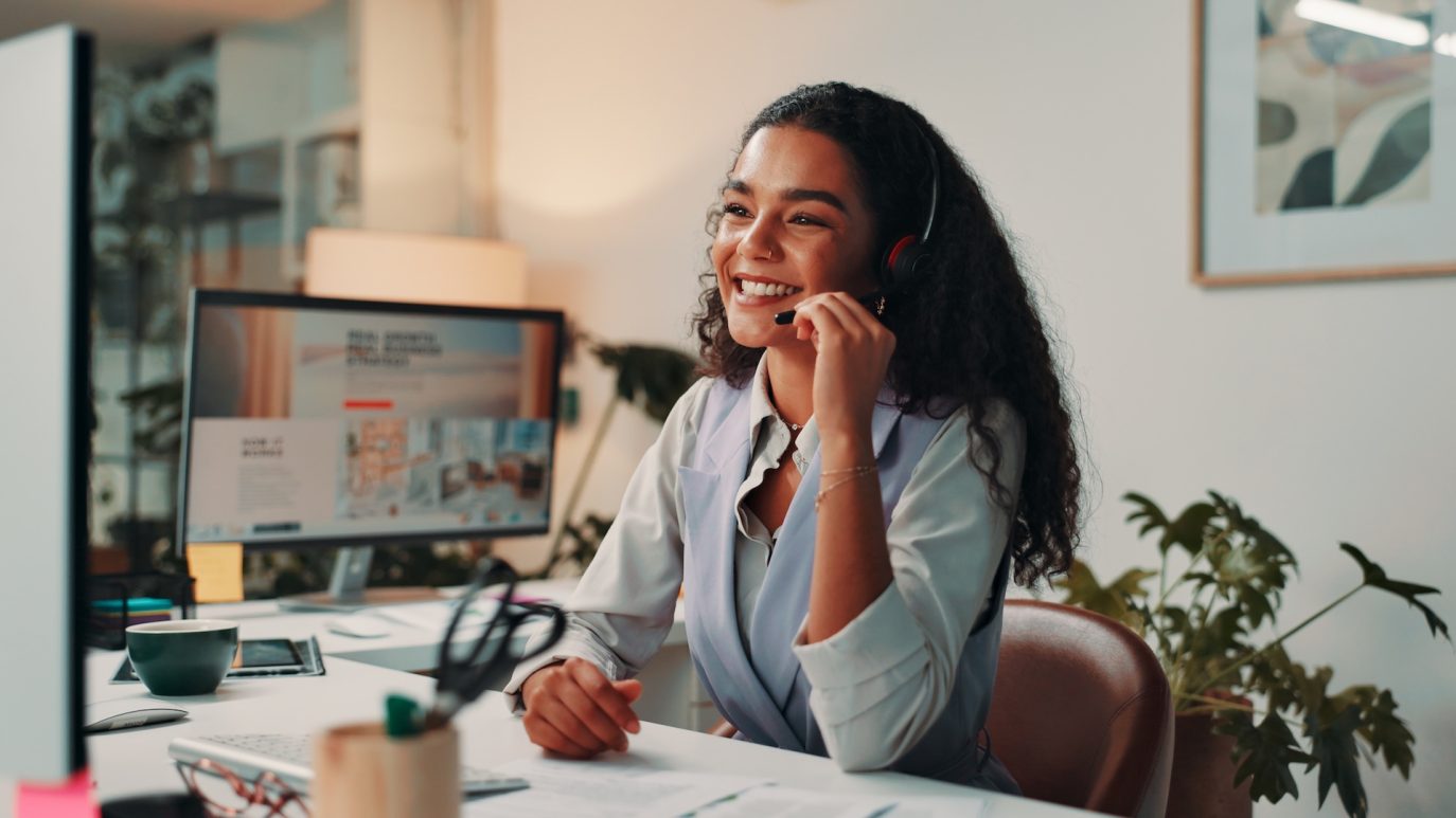 Smiling woman in headset providing customer support at her desk