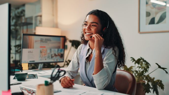 Smiling woman in headset providing customer support at her desk