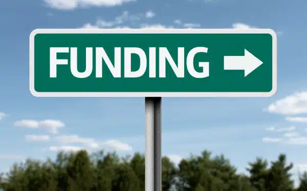 Green road sign with the word "FUNDING" and a right-pointing arrow