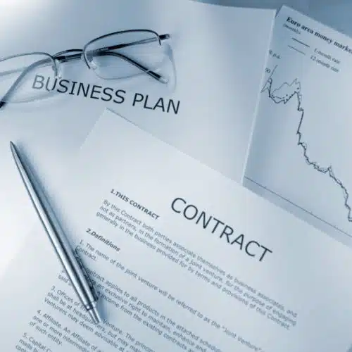 Documents labeled "Business Plan" and "Contract" with a pen and glasses on a desk