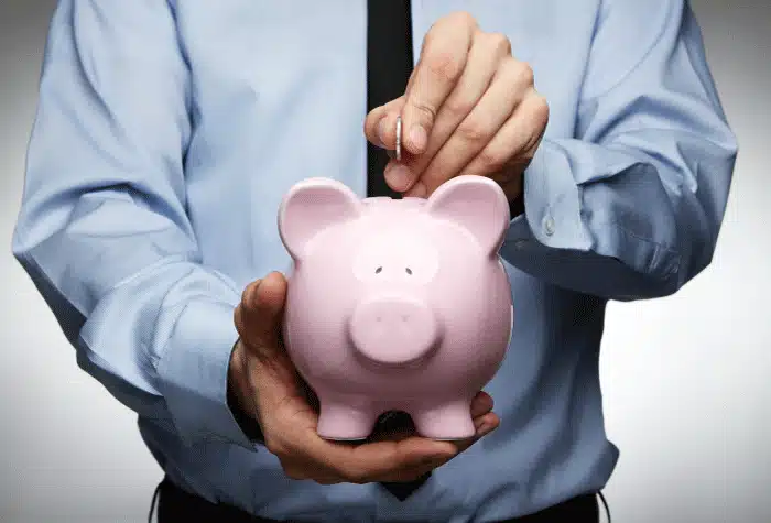 Businessman placing a coin into a pink piggy bank