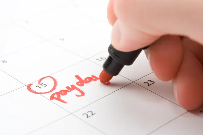 Hand circling payday on a calendar with red marker