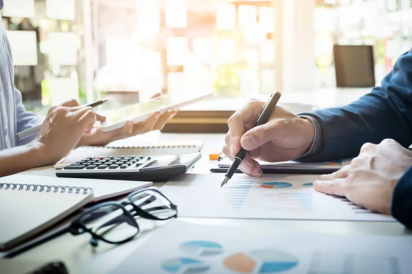 Two professionals reviewing financial charts with a calculator and tablet at a desk