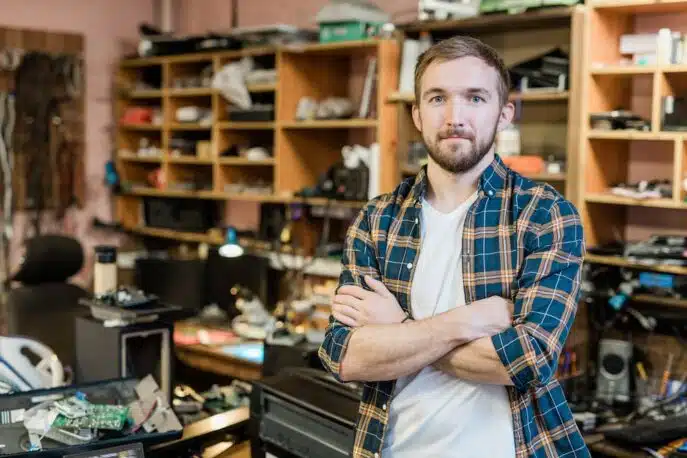 Confident man standing in an electronics workshop with arms crossed
