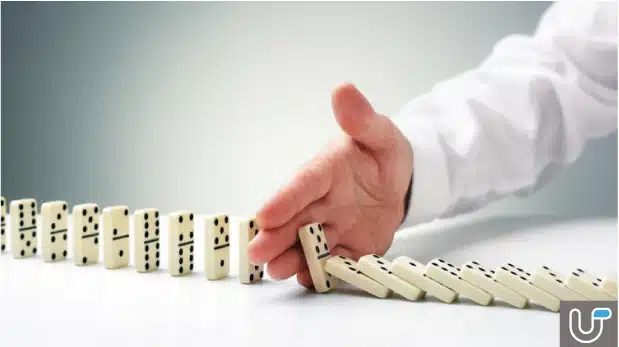 Hand stopping falling dominoes, symbolizing risk management