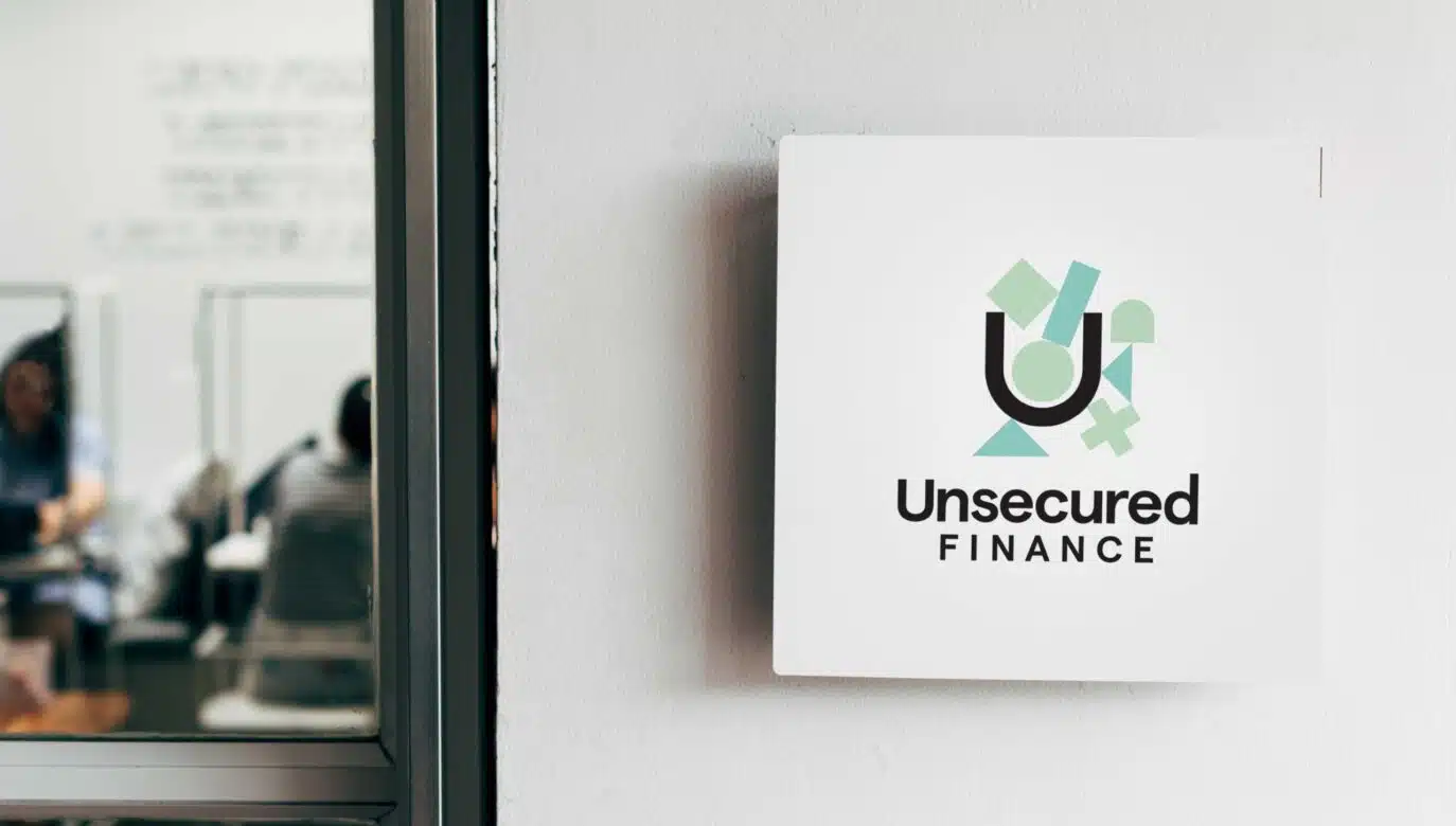 Unsecured Finance office sign mounted on wall with blurred staff working in background
