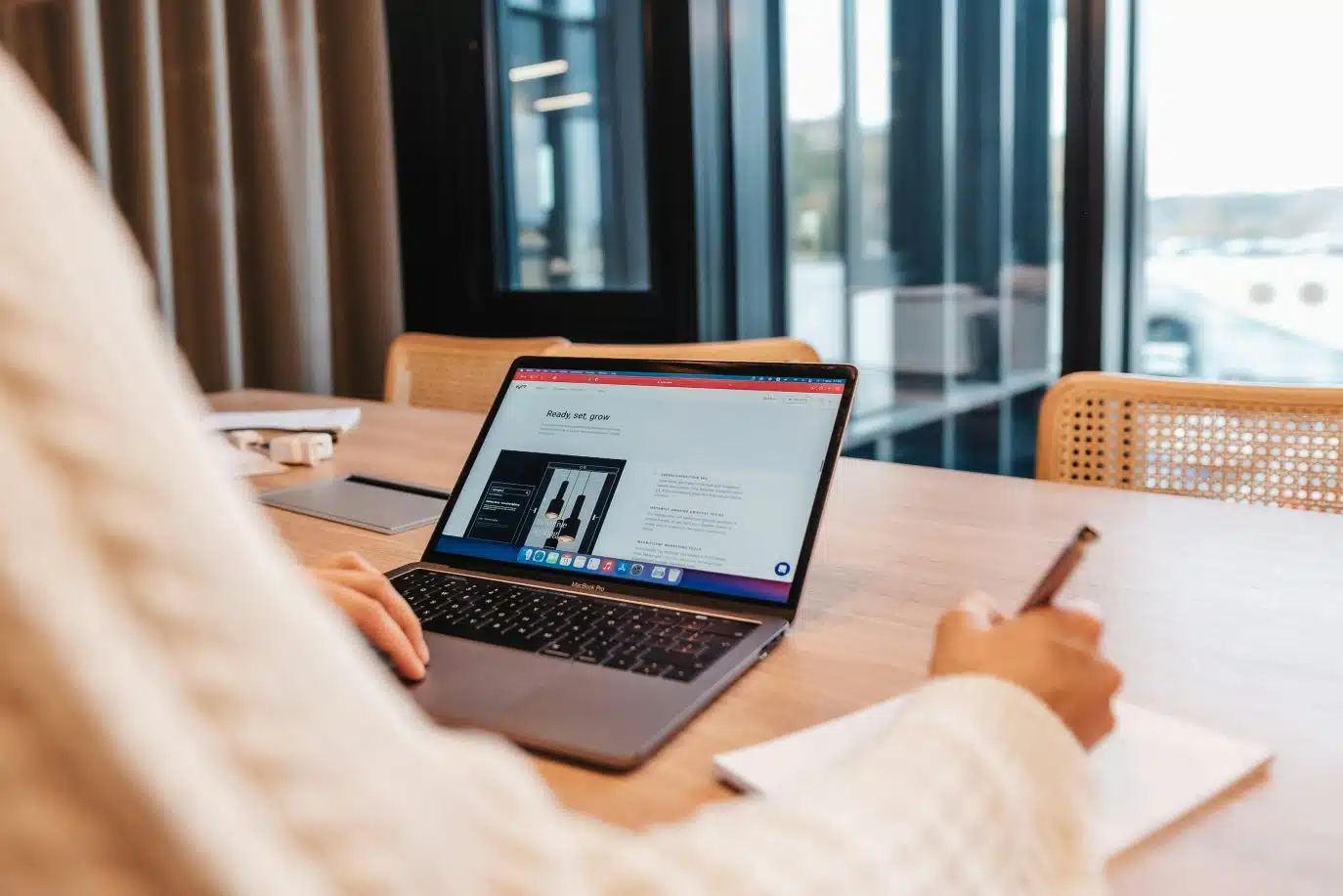 Person taking notes while viewing a growth strategy on a laptop in a modern office.