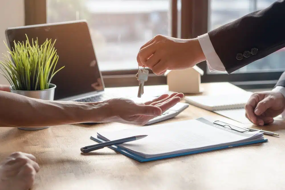 Close-up of a businessperson handing over keys during a contract signing