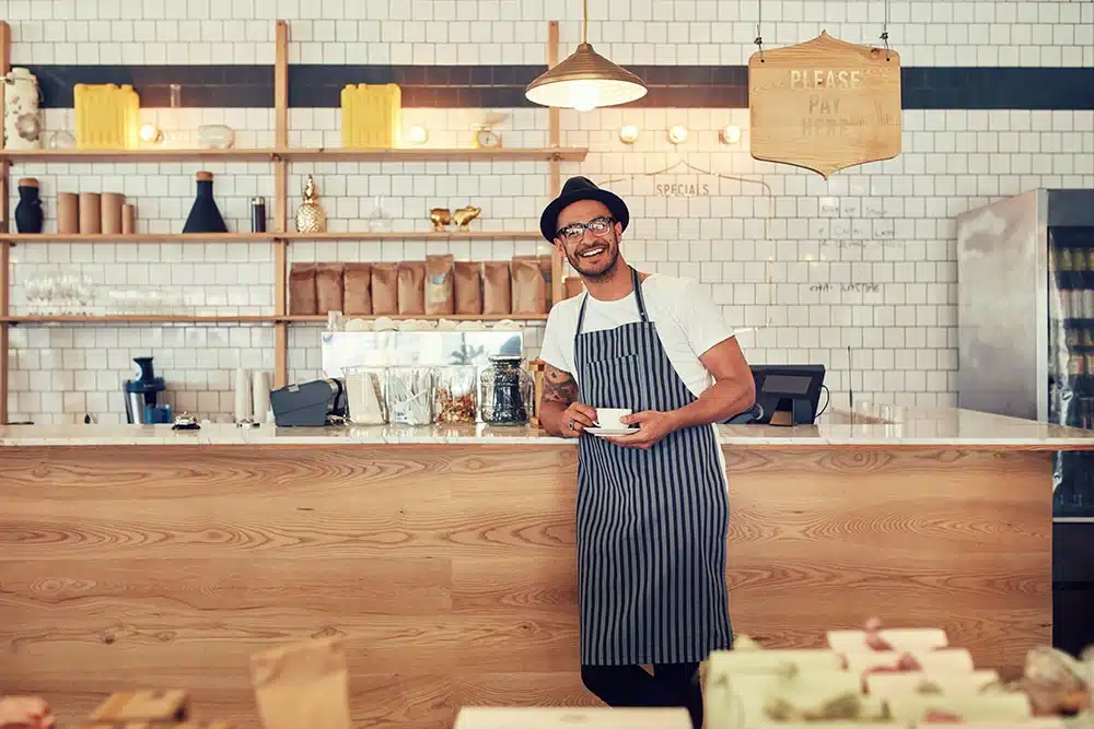 Smiling man standing in a coffee roasting business wearing an apron