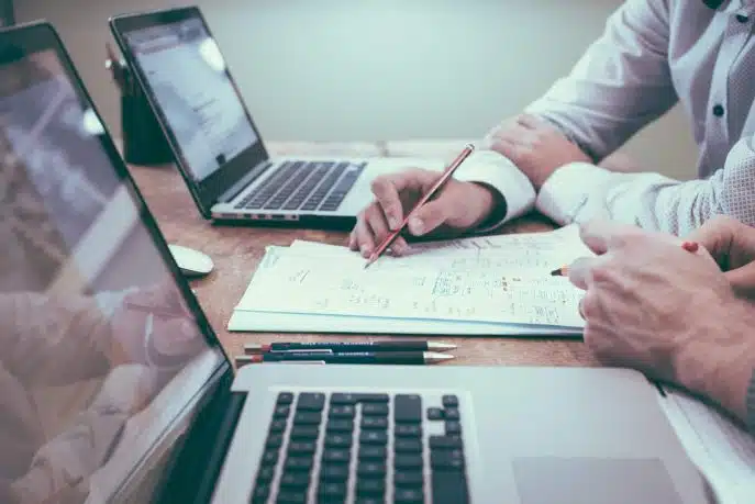 Business professionals reviewing data and strategy notes at a desk with laptops