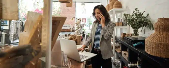 Businesswoman managing her store while talking on the phone and using a laptop