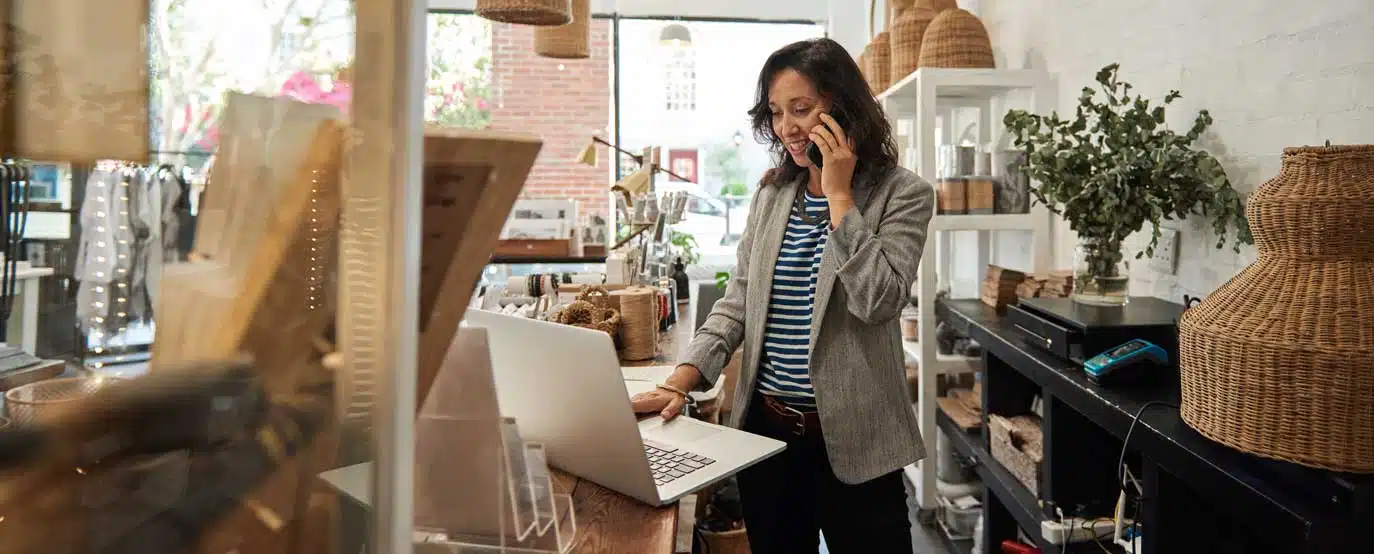 Businesswoman managing her store while talking on the phone and using a laptop