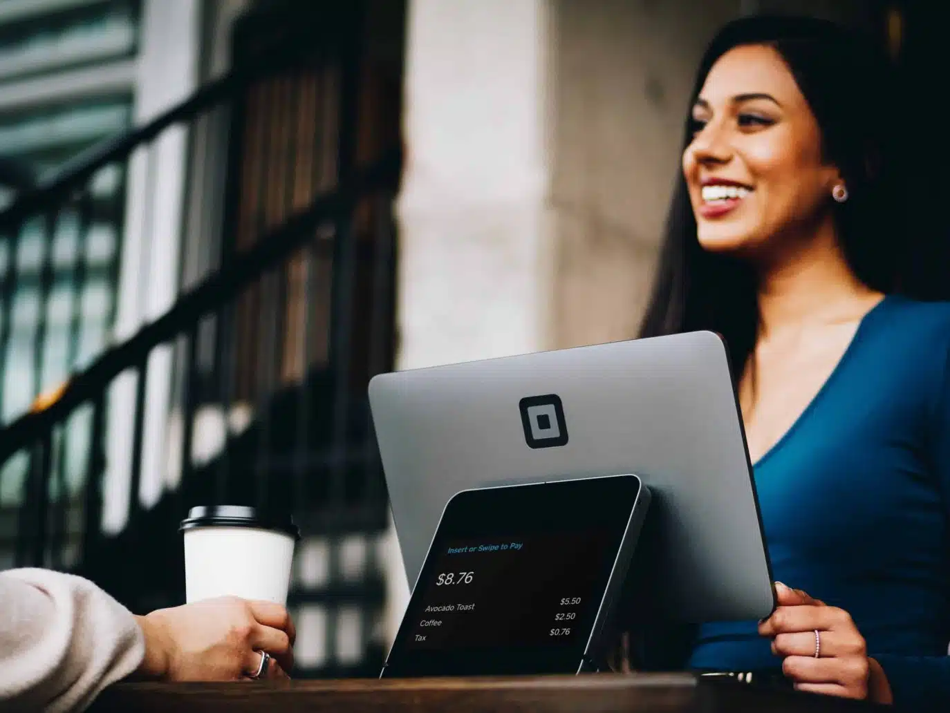 Smiling barista or retail worker processing payment at a coffee shop