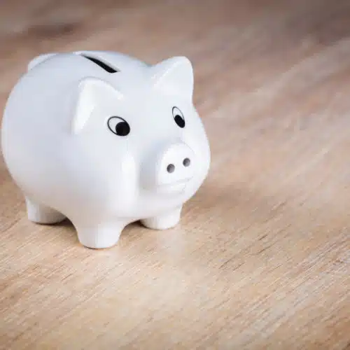 White ceramic piggy bank on a wooden surface