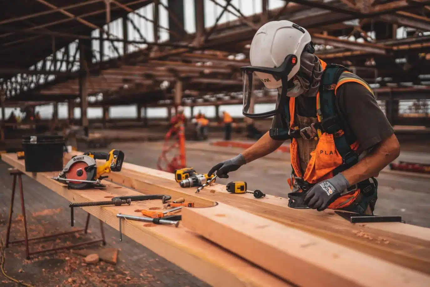 Construction worker using power tools on timber inside an industrial building site