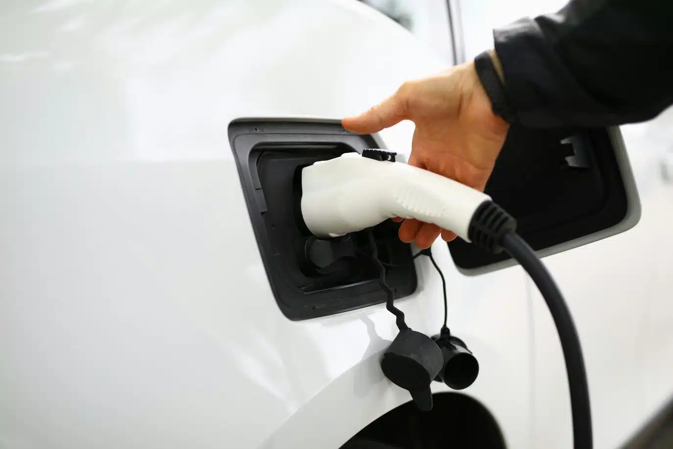 Person plugging a charging cable into an electric vehicle.