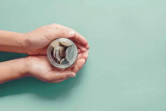 Hands holding a small jar filled with coins