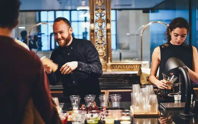 Barista duo preparing drinks behind a café counter with a smiling male barista and focused female barista