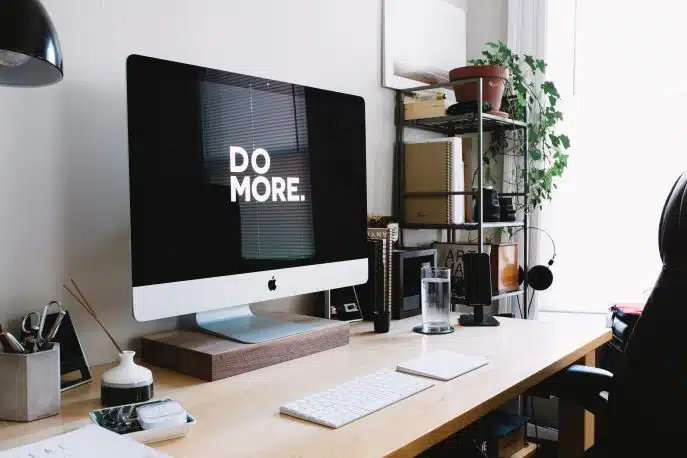 Modern home office workspace with an iMac displaying the words "DO MORE."
