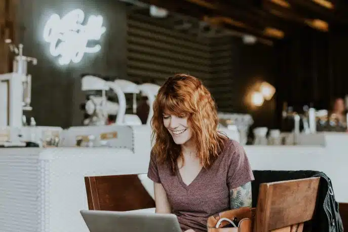 Smiling woman using a laptop in a stylish cafe setting