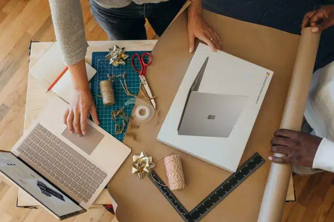 Small business team wrapping a product for delivery with a laptop and packaging supplies