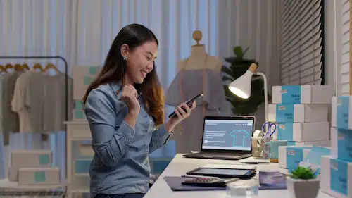 Excited online store owner celebrating success while using smartphone