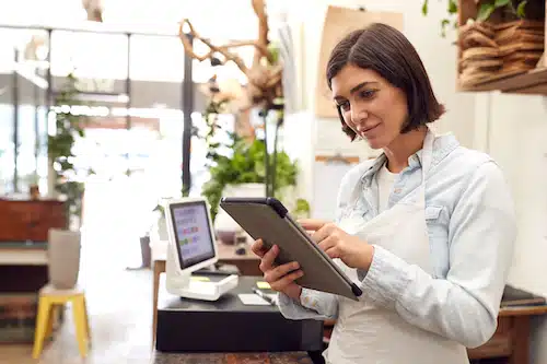 Small business owner using a tablet behind the counter of her shop