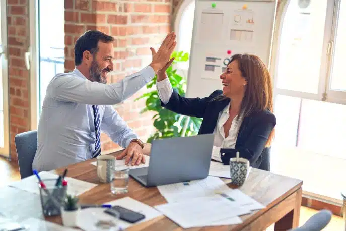 Business partners high-five during a successful meeting at a modern office desk