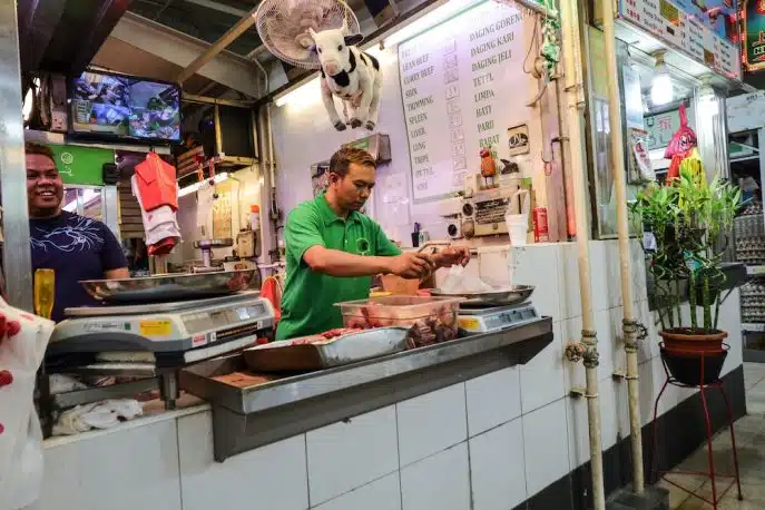 Man preparing meat at a butcher stall in an Asian wet market
