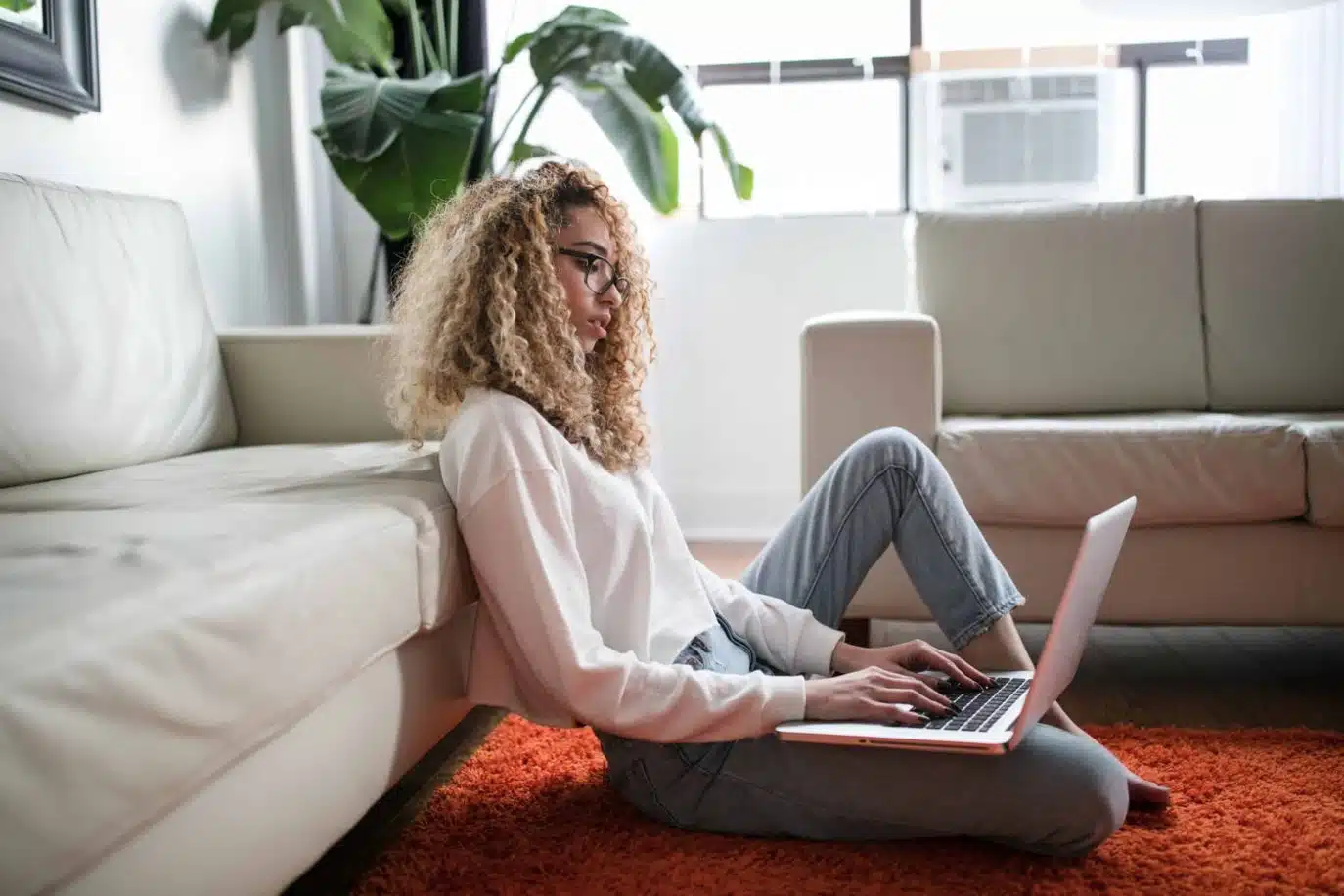 Young woman working on a laptop while sitting on the floor at home