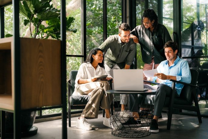 Group of diverse business professionals collaborating around a laptop in a modern office