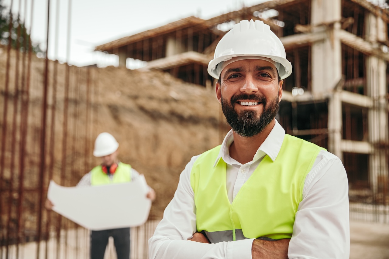 Construction business owner smiling confidently at a building site