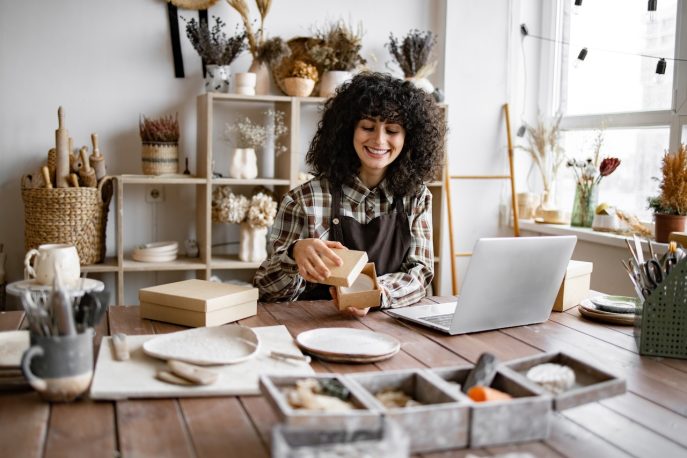 Small business owner packaging products at her craft workspace